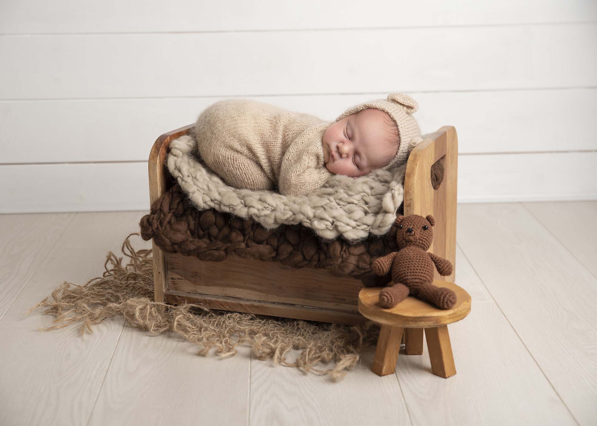 newborn baby boy sleeping on a bed with teddy outfit photographed by Newborn Photographer Manchester