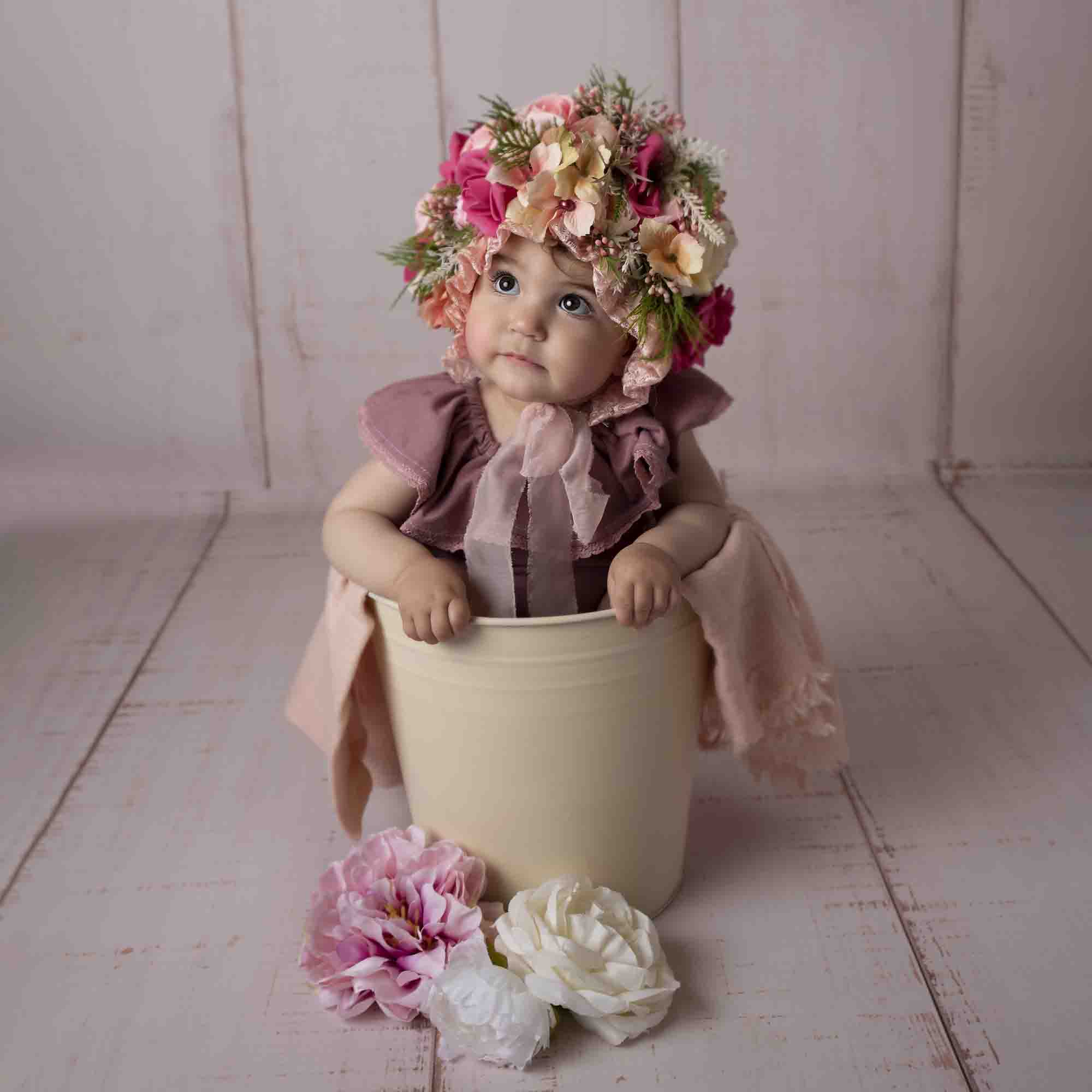 one year old baby girl sitting in cream bucket photographed by Newborn Photographer Manchester