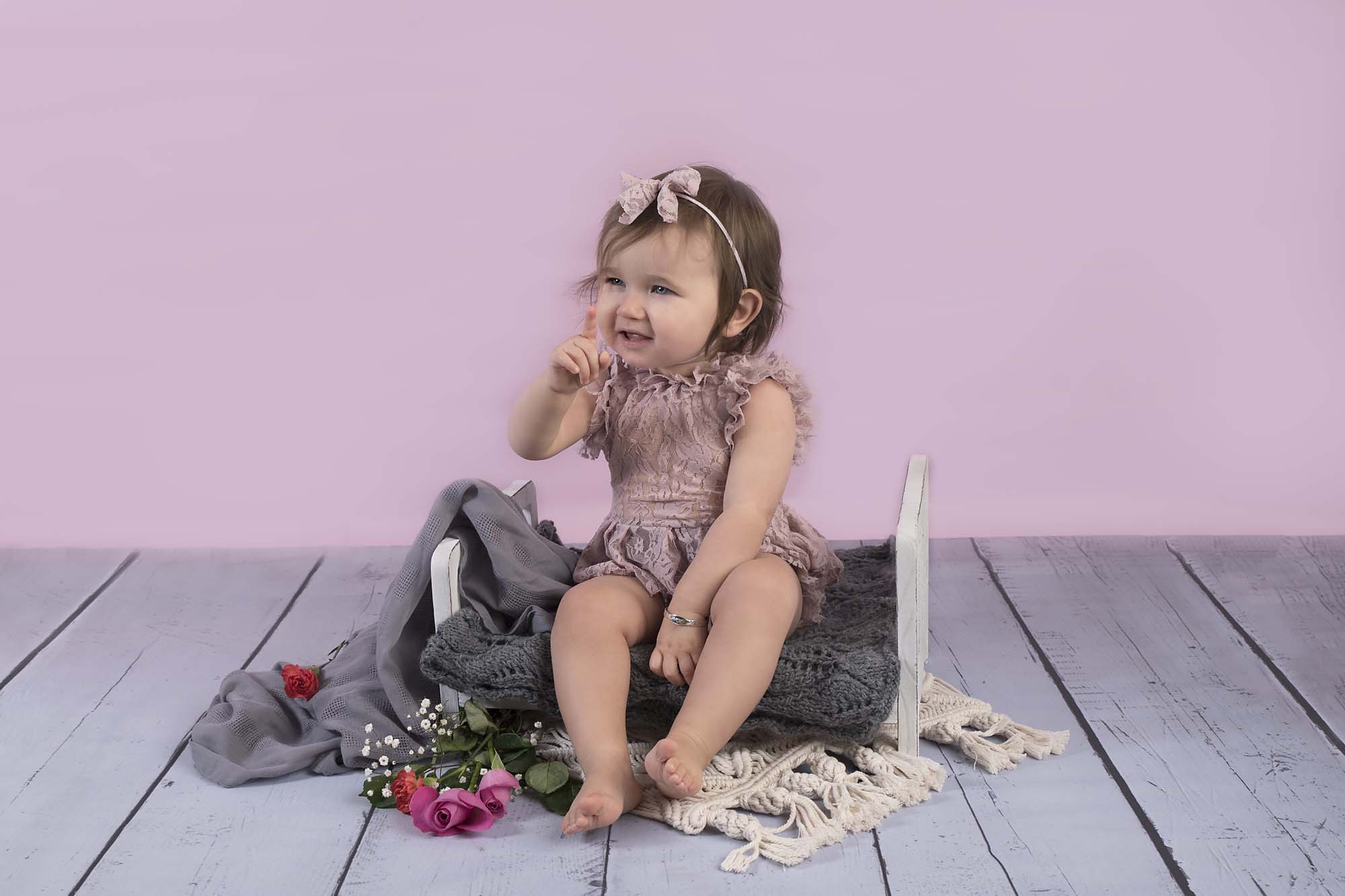 Baby girl is having fun on a bed photographed by Baby Photographer Manchester