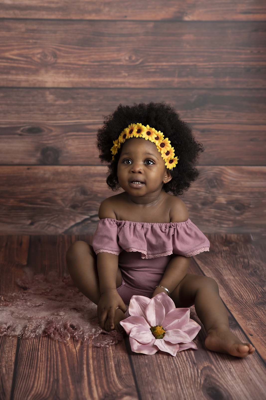 baby girl is sitting with flower photographed by Baby Photographer Manchester