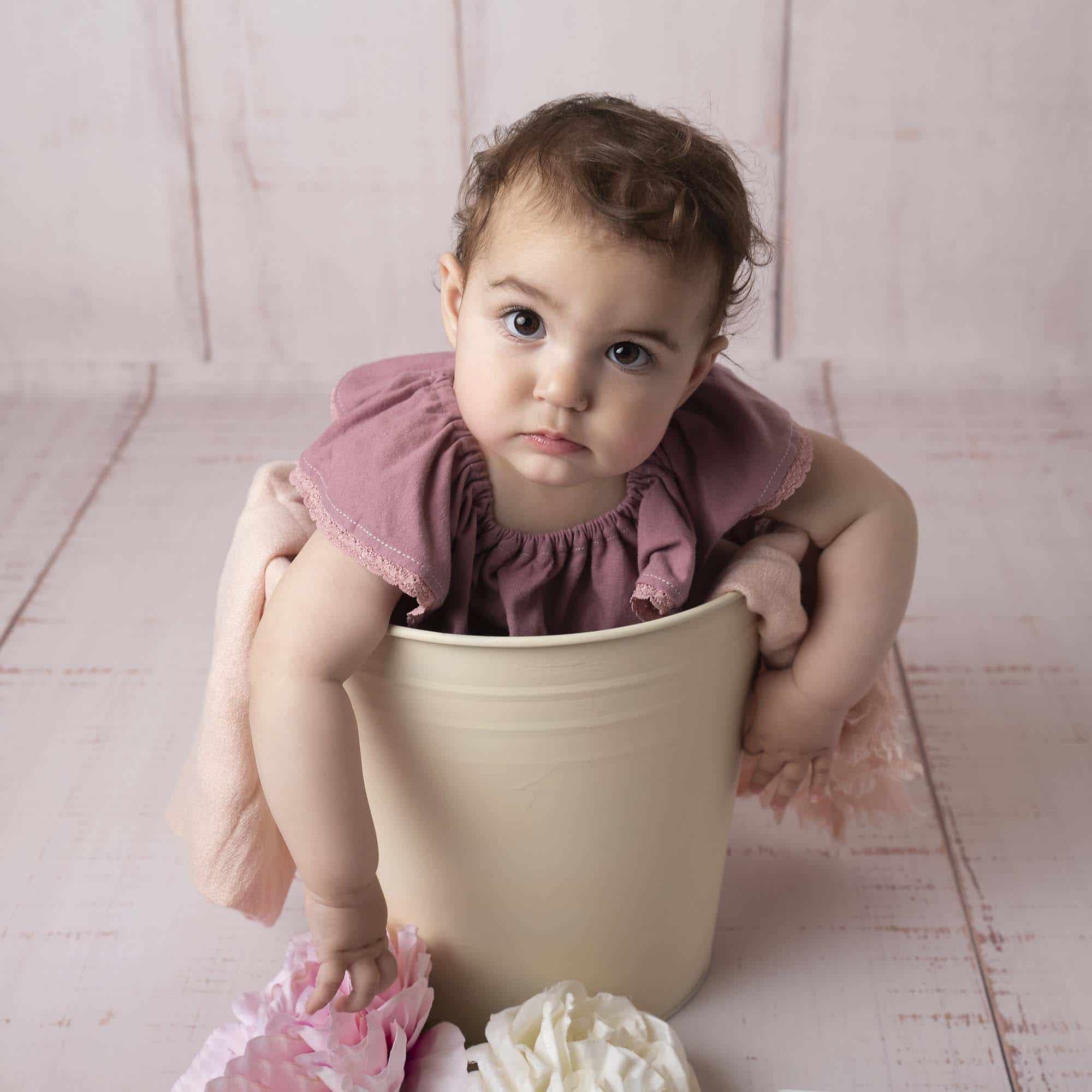 little girl is sitting in bucket photographed by Baby Photographer Manchester