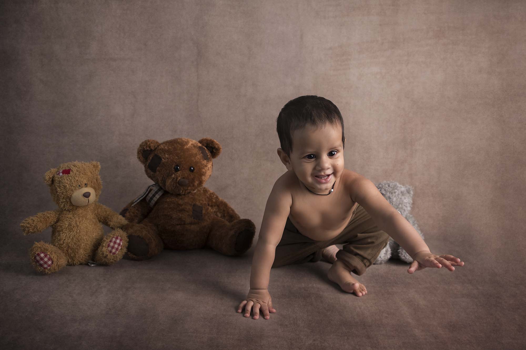 baby boy is sitting with teddy bears photographed by Baby Photographer Manchester
