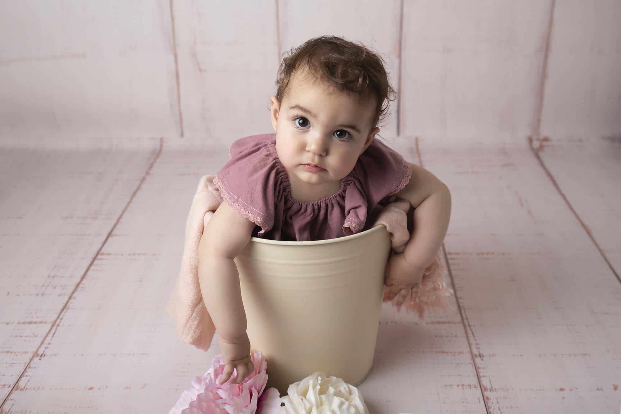 baby girl sitting in bucket photographed by Baby Photographer Manchester