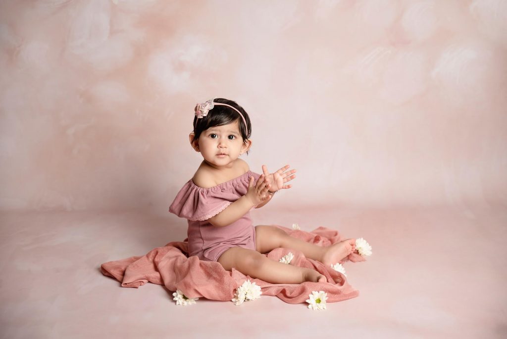 sitter little girl with peachy floral background taken by baby photography Manchester