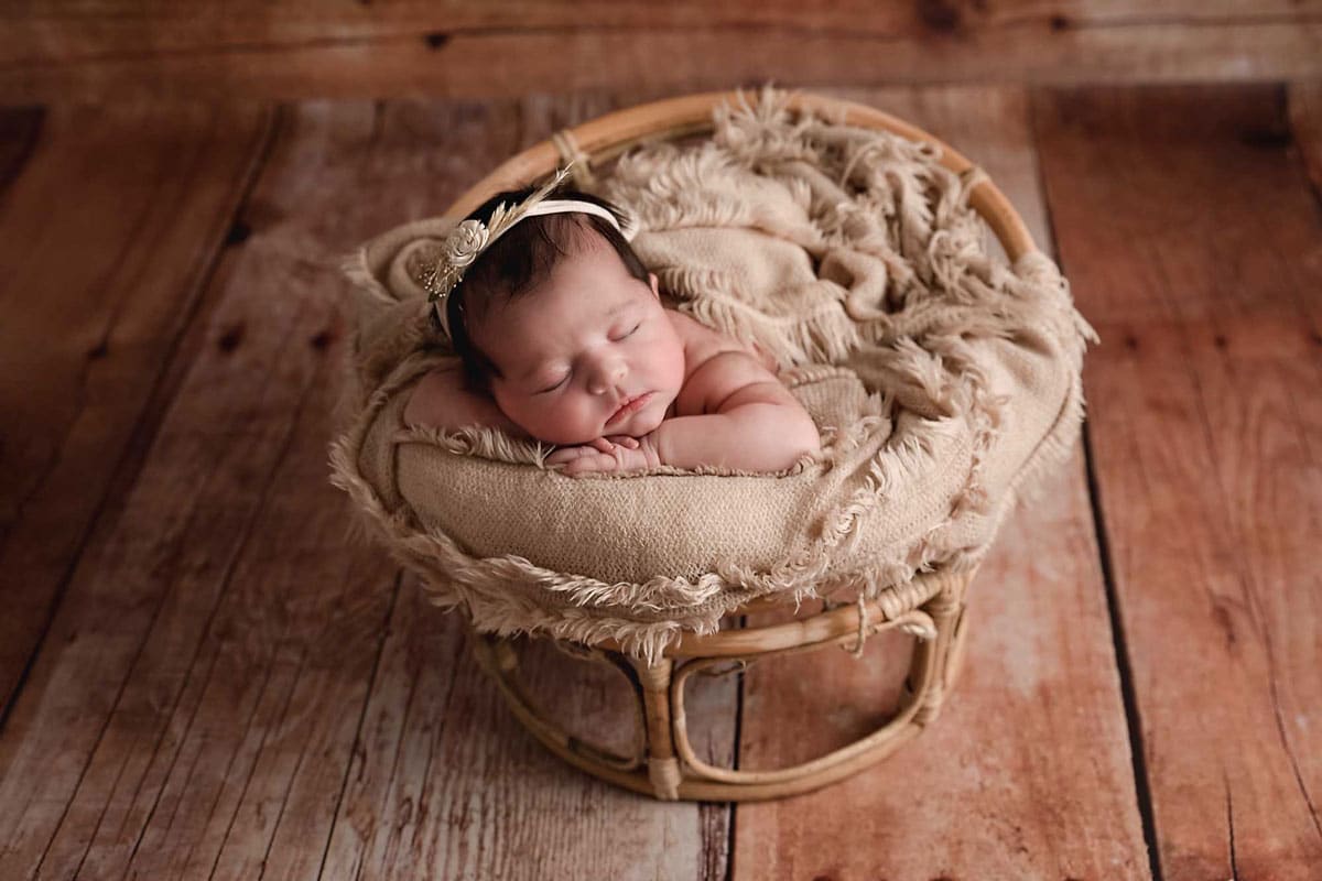 newborn baby in a basket and wooden background taken by newborn photography manchester