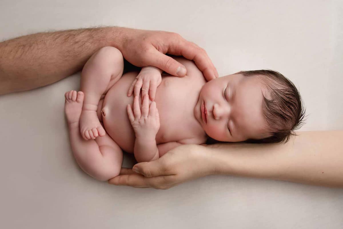 newworn baby girl held by parents taken by newborn photography manchester