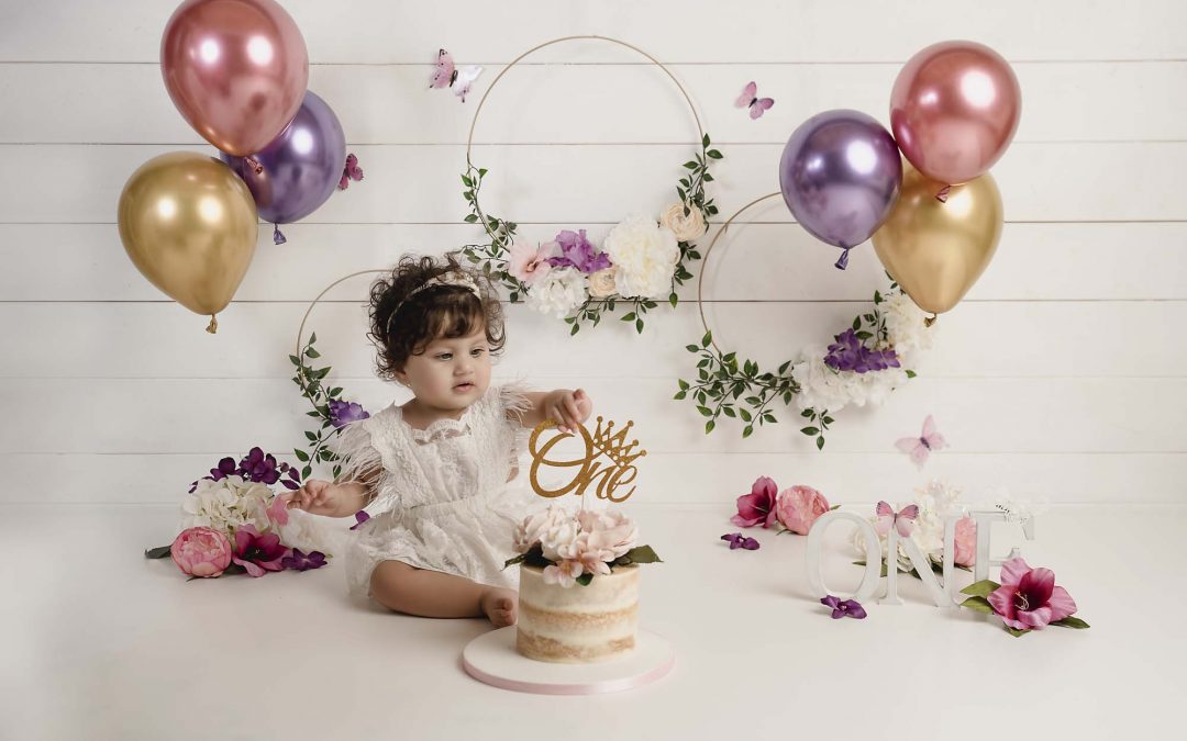 sitter little girl with cake and baloons by cake smash photography Manchester