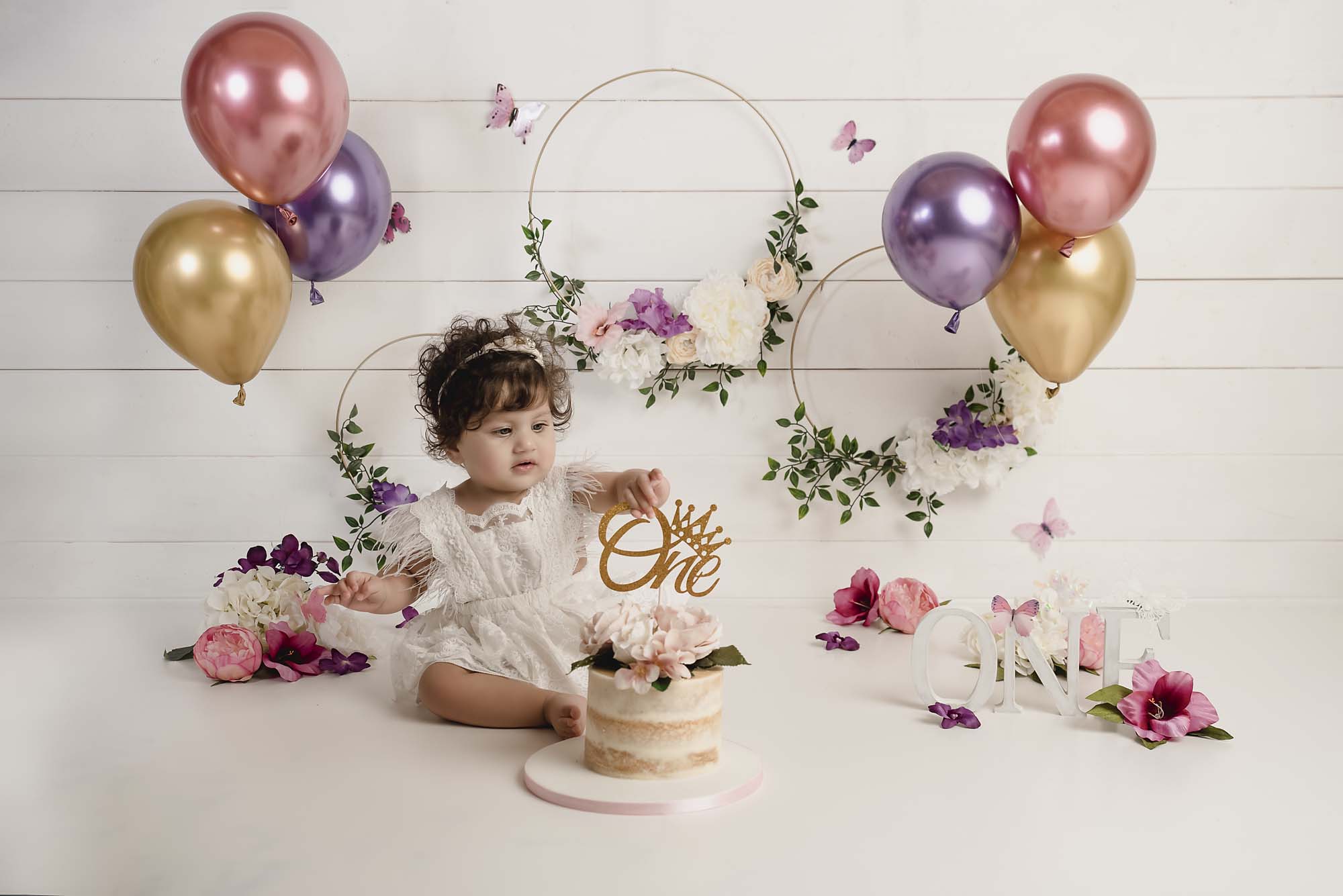 sitter little girl with cake and baloons by cake smash photography Manchester