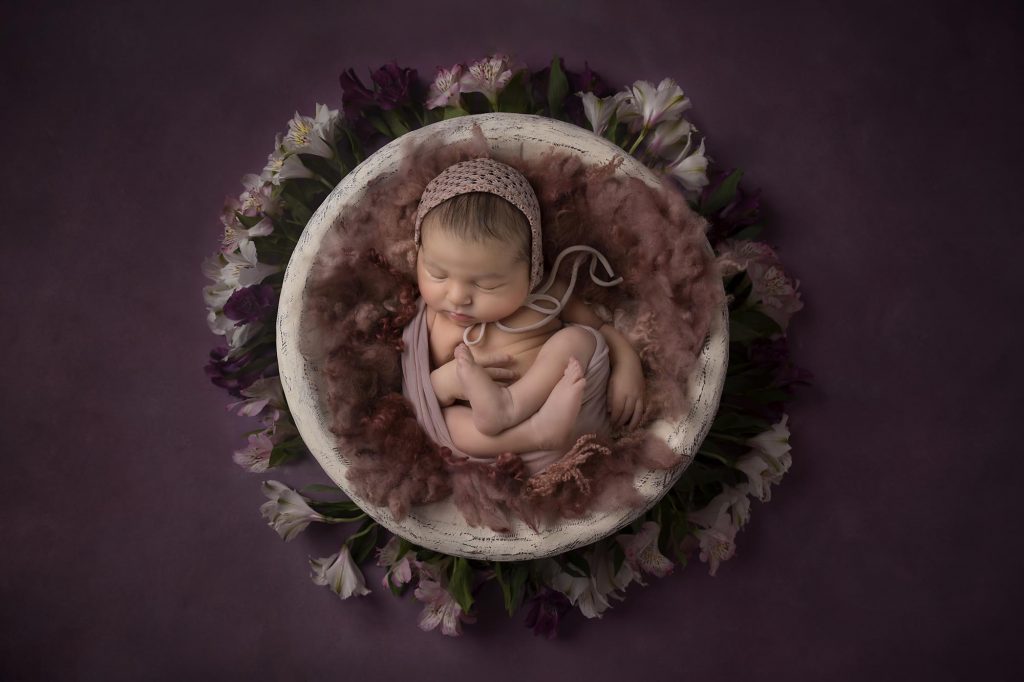 newborn baby girl is sleeping in a wooden bowl taken by newborn photography manchester