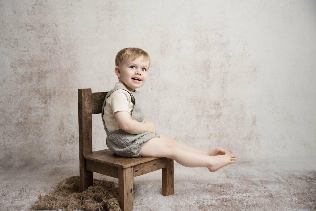 sitter session with a one year old boy sitting by a creamy background in a baby photography studio in manchester