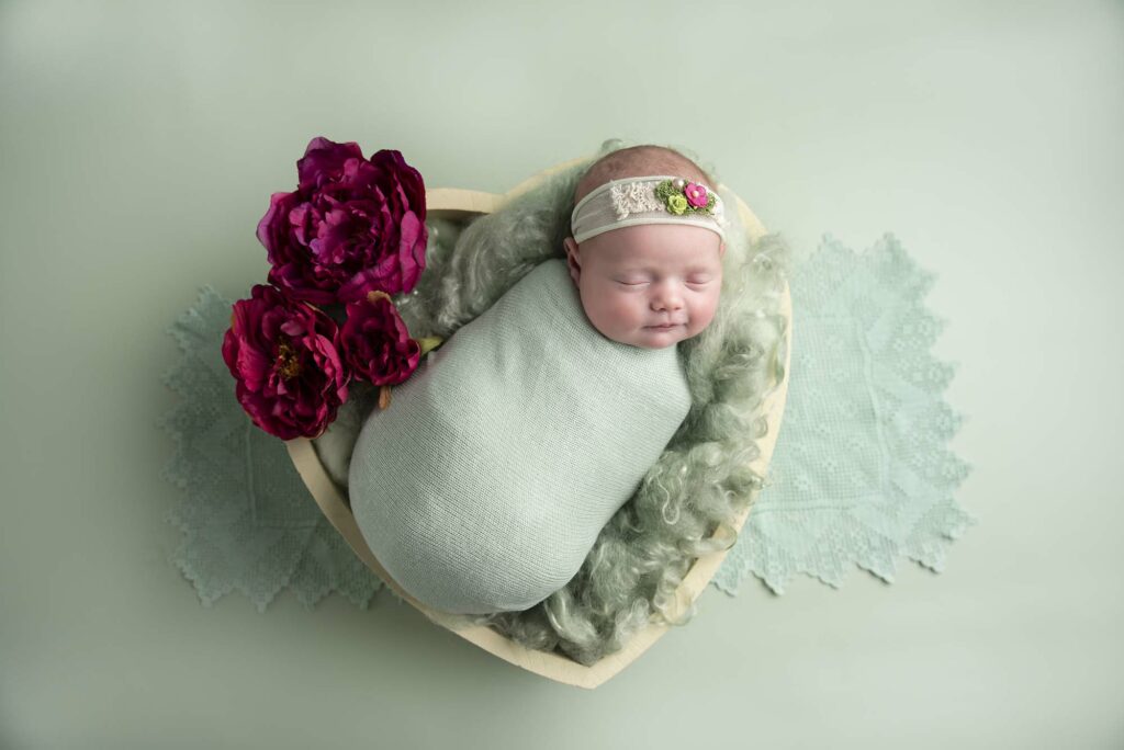 newborn photography baby in mint set in white bowl surrounded with flowers