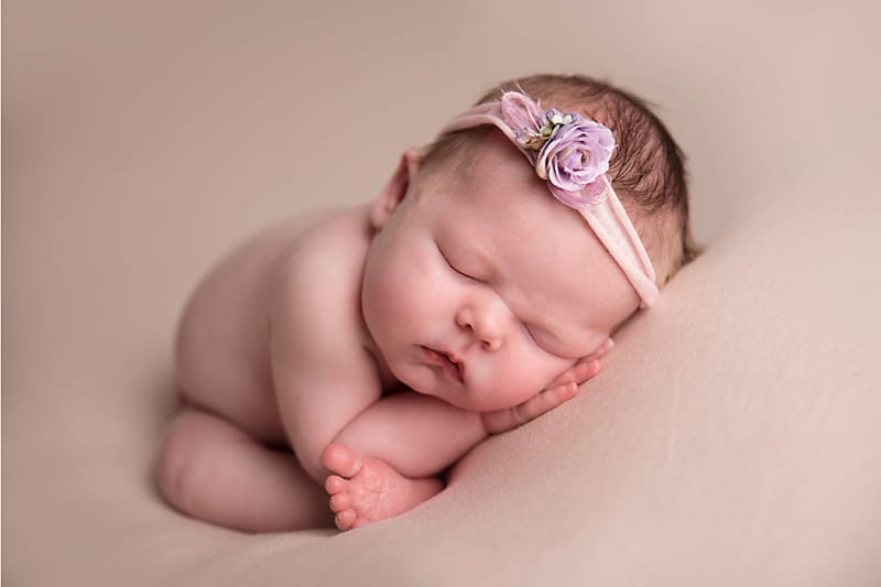 nebworn baby sleeping on her belly on a creamy background taken by newborn Photographer Dora Horvath Photography