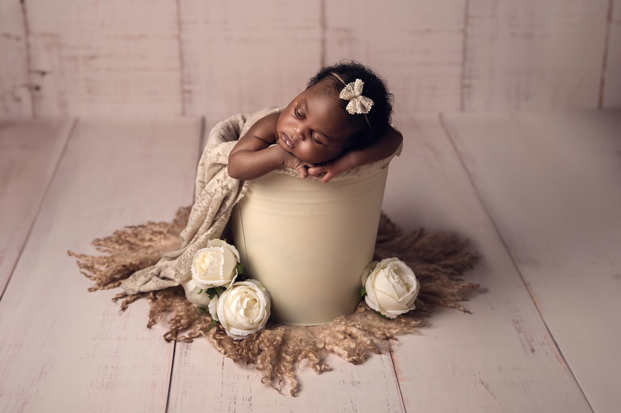 a baby sleeping in a bucket with white flowers